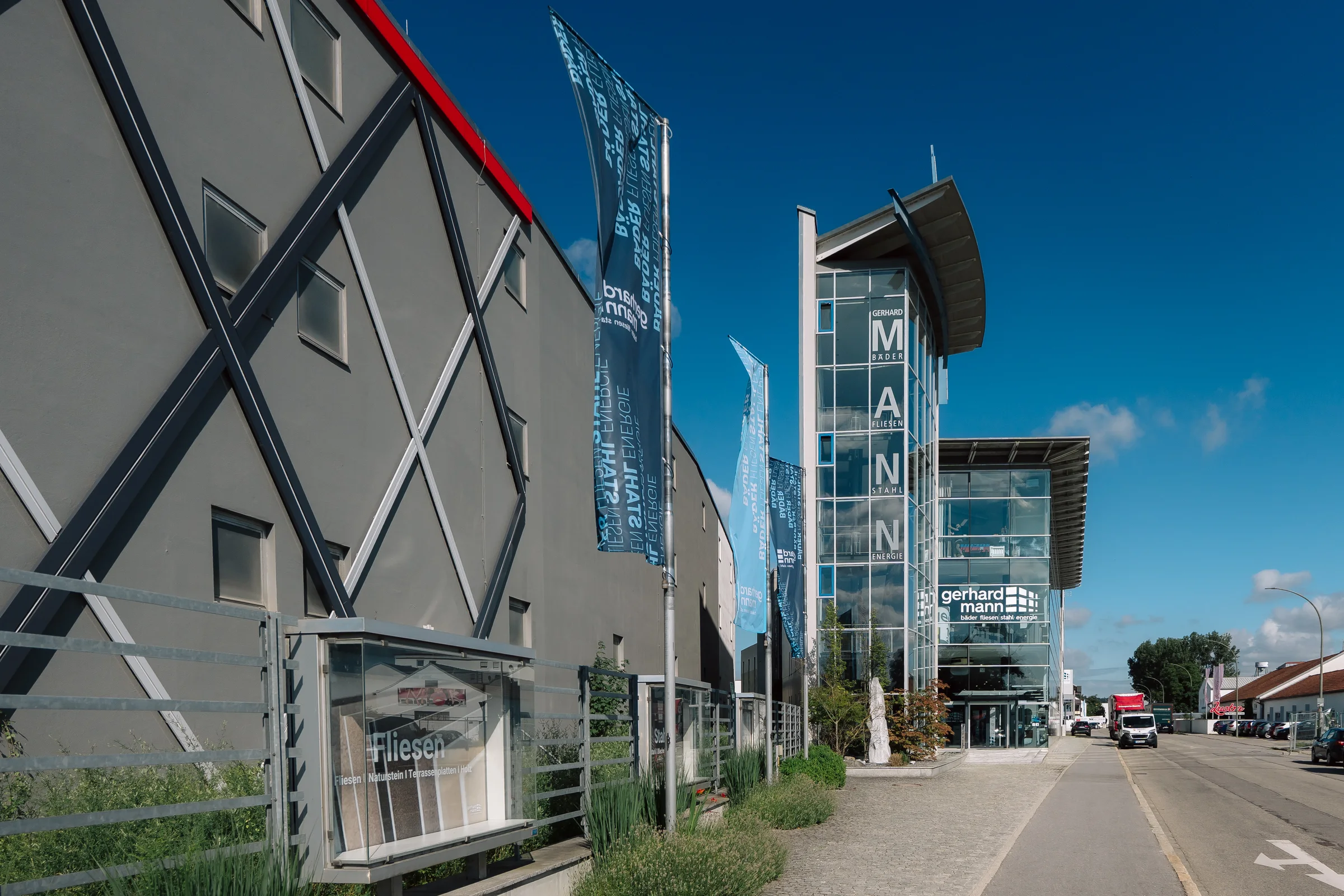 Gerhard-Mann-Standort an der Benzstraße mit Fahnen, gläsernem Treppenturm und Ausstellungsgebäude