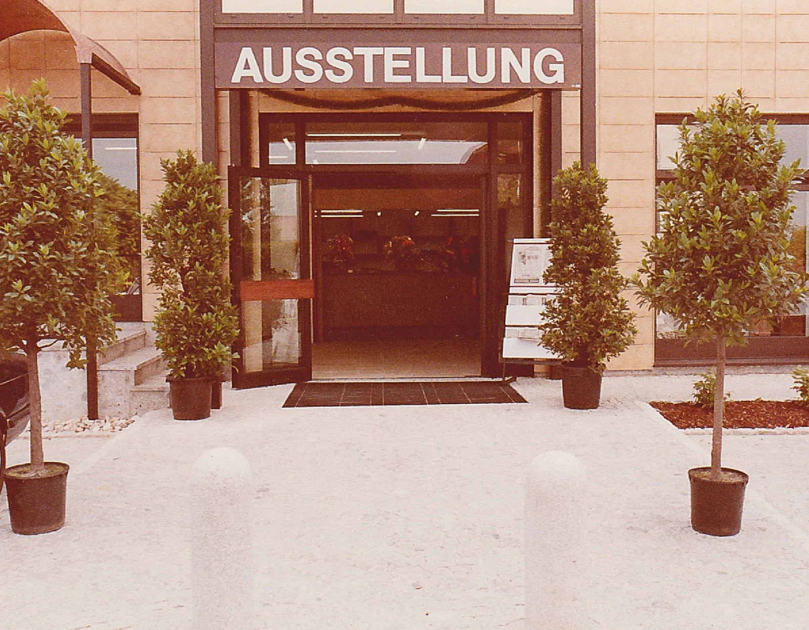 Eingang der neuen Bäderausstellung 1985 mit dem Schriftzug Ausstellung über der Glastür, davor Bäumchen in Kübeln